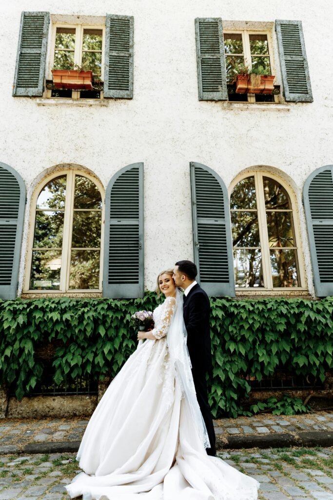 Elegant bride and groom share a joyful moment outside a charming Parisian building.